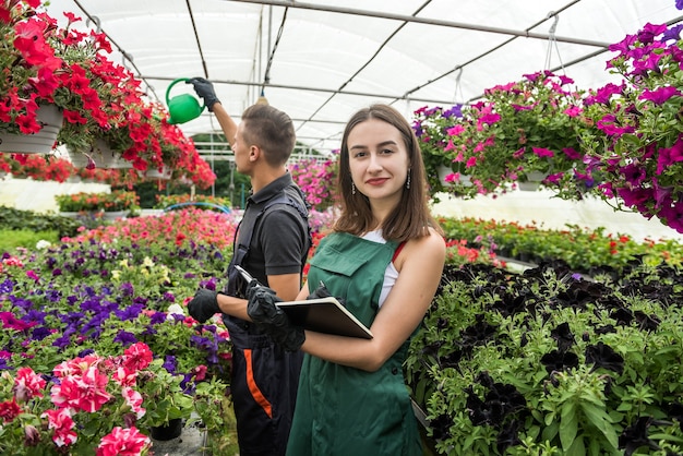 Coppia di fioristi che si prendono cura dei fiori in serra industriale