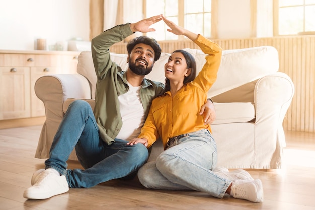 Foto coppia che forma una forma di tetto con le mani sedute a casa