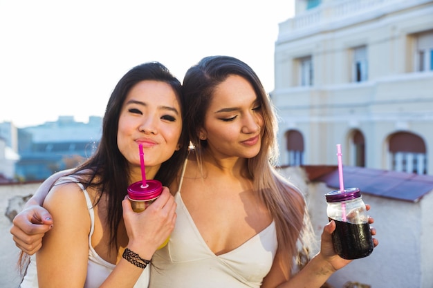 屋外で飲み物を持っている友人のカップル