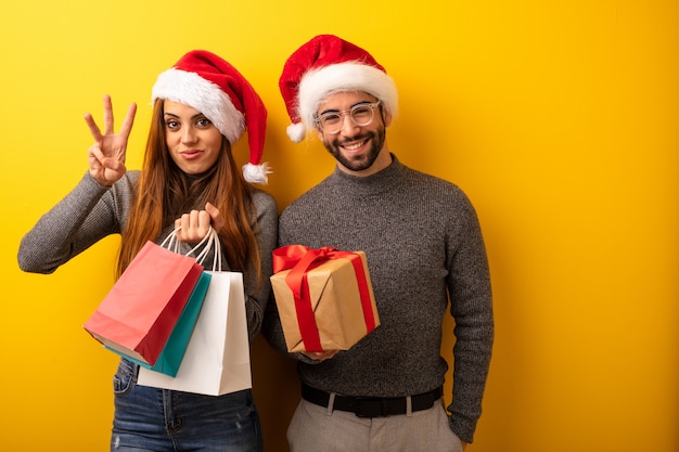 Couple or friends holding gifts and shopping bags showing number three