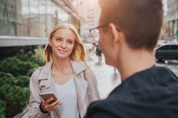 Couple or friends laughing funny and having fun with a smart phone in a big city street