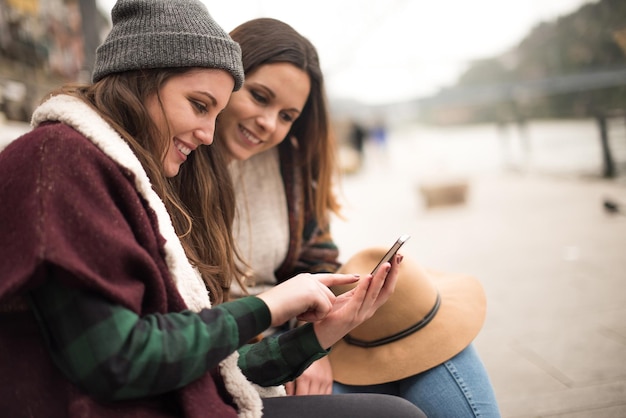 Coppia di amici con uno smartphone nella via della città