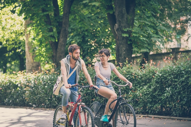 couple of friends young  man and woman riding bike