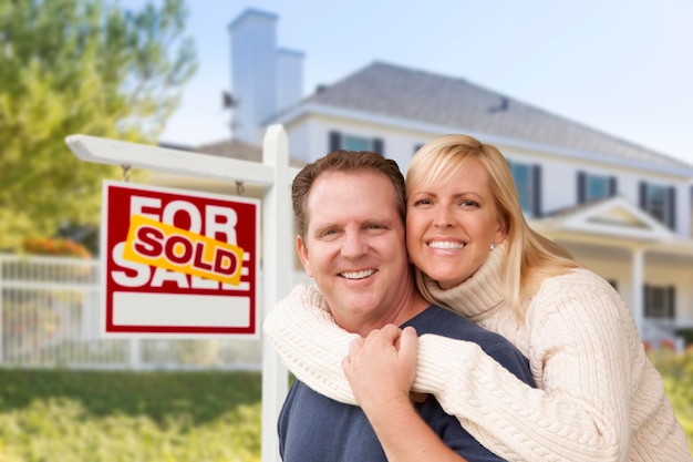 Photo couple in front of new house and sold sign