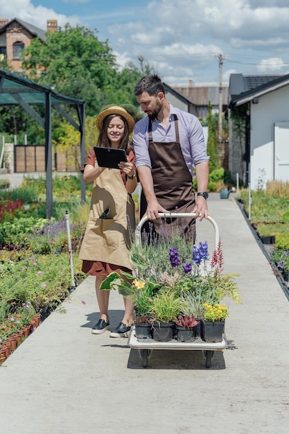 A couple of gardeners select plants for a customer at a garden center