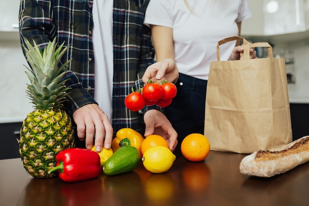 Una coppia prende gli acquisti che hanno comprato al supermercato per cucinare il pranzo in cucina.