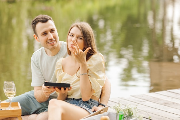 Couple gets great pleasure eating chocolates during romantic picnic in nature . Sweet life. Happiness and serenity. Beautiful moments of life. Super day. Romantic relationships. Tenderness and care.