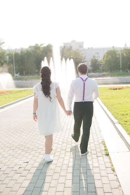 A couple of a girl and a guy hold hands and walk around the city