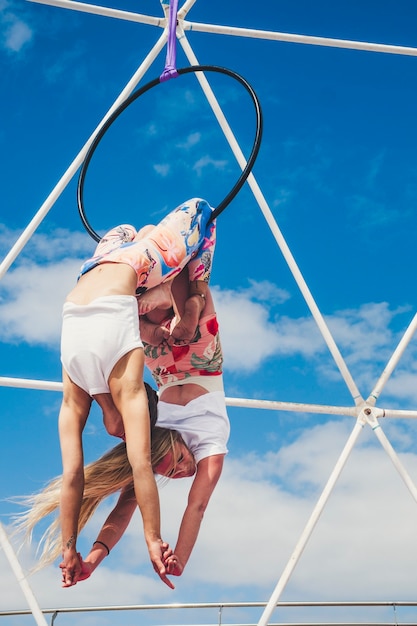 Couple of girls in reverse position doing acrobatic fitness exibition show activity outdoor with circle in balnced positions for healthy alternative sport lifestyle