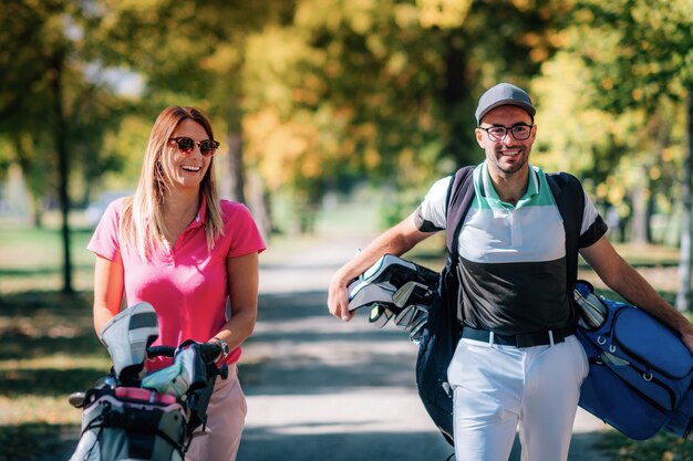 Couple on the golf course walking to the next hole enjoying a beautiful sunny autumn day