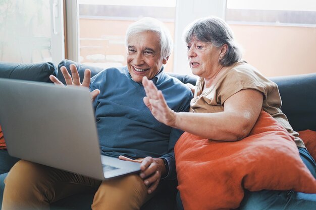 A couple of grandparents waved goodbye to their grandchildren through the computer screen during a video call. Concept of families keeping in touch through new technological means.