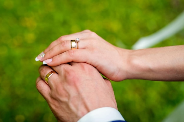 結婚指輪とカップルの手婚約中のカップルは、新しいダイヤモンドの指輪を示す手を握ります