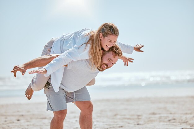 Couple happy and beach holiday with travel fun and playful together anniversary vacation by the ocean with freedom and comedy Happiness man with woman and laugh love and piggyback on Bali coast