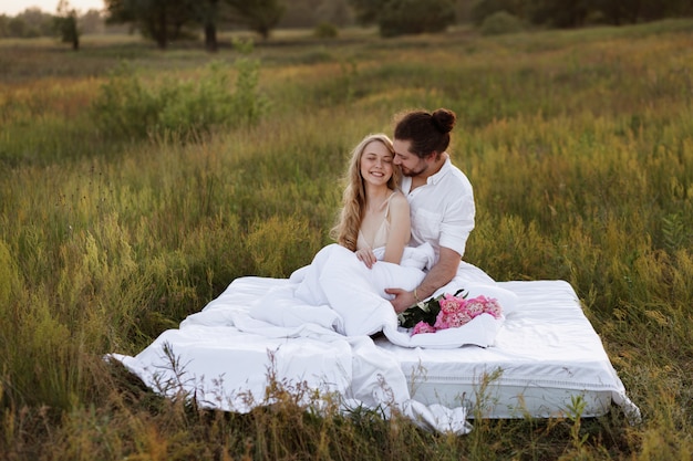 A couple happy in bed at dawn in a field.