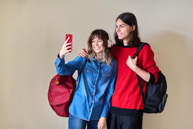 Couple of happy teenage students taking selfie using smartphone