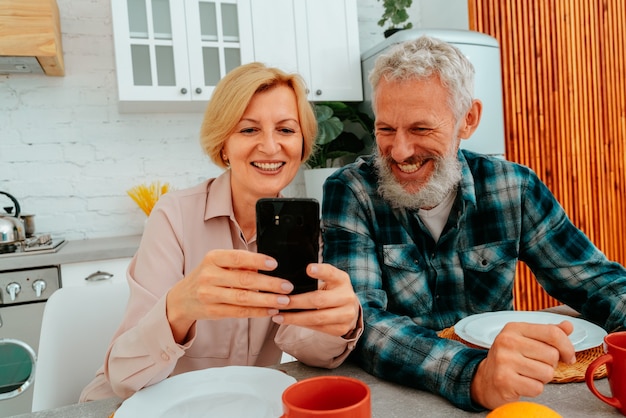 カップルは家で朝食をとり、スマートフォンから何かを読みます