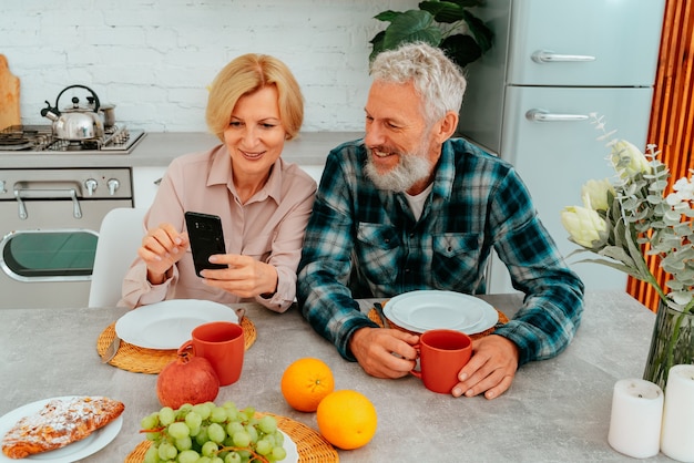 カップルは家で朝食をとり、スマートフォンから何かを読みます