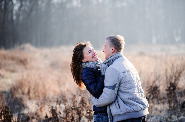 Couple has fun and laughs. kiss. Young hipster couple hugging each other in winter park. Winter love story, a beautiful stylish young couple. Winter fashion concept with boyfriend and girlfriend.