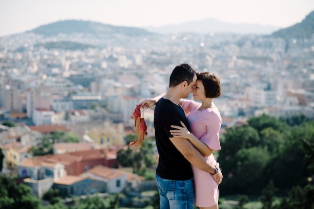 Couple have a date on the peak of the hill with panorama view on the city kissing each other