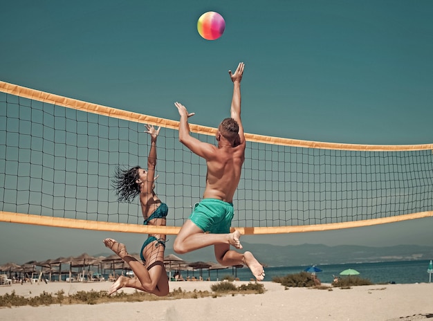 Couple have fun playing volleyball young sporty active couple\
beat off volley ball play game on summer day