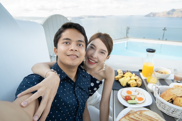 Couple having breakfast tourist take a selfie on terrace hotel outdoor