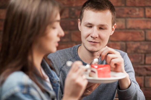 Foto coppia che mangia la torta contro un muro di mattoni