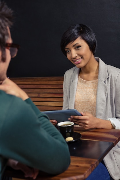 Couple having a coffee together and using tablet