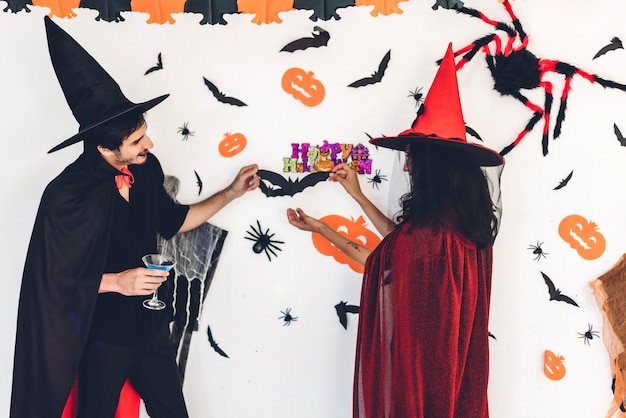 Couple having fun holding pumpkins and wearing dressed carnival halloween costumes