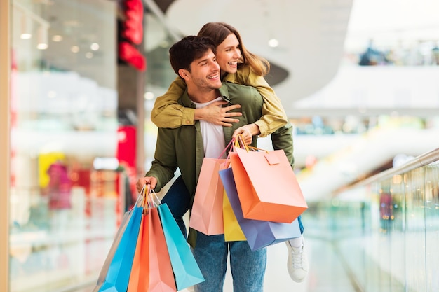 Couple Having Fun Shopping Together With Shopper Bags In Hypermarket