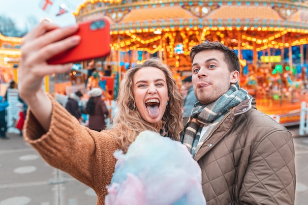 Couple having fun and taking a selfie at amusement park in london