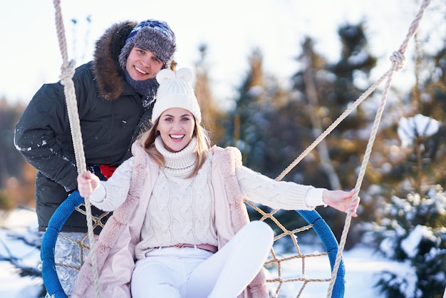 Couple having fun in winter snow on swing. High quality photo