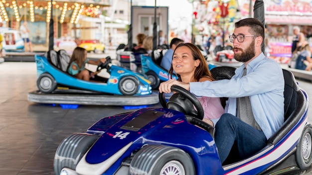 Couple having fun with bumper cars at the amusement park