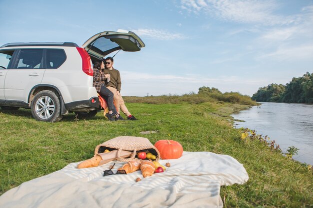 Couple having picnic date at river beach autumn warm day copy space