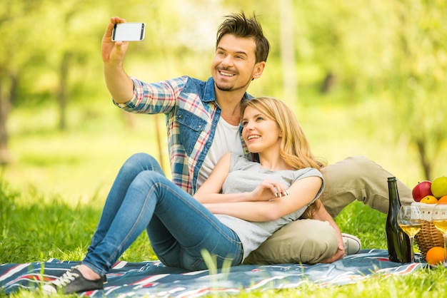 Coppia fare picnic nel parco e fare selfie.