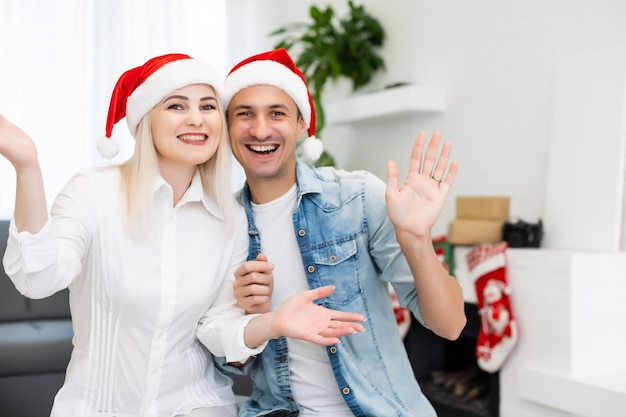 Coppia che fa una videochiamata il giorno di natale seduta su un divano nel soggiorno di casa