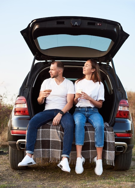 Coppia che beve vino nel bagagliaio dell'auto