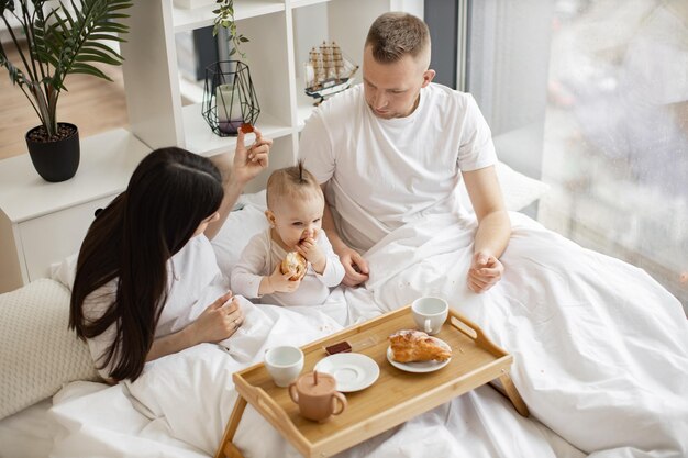 Couple helping daughter with croissant during morning time