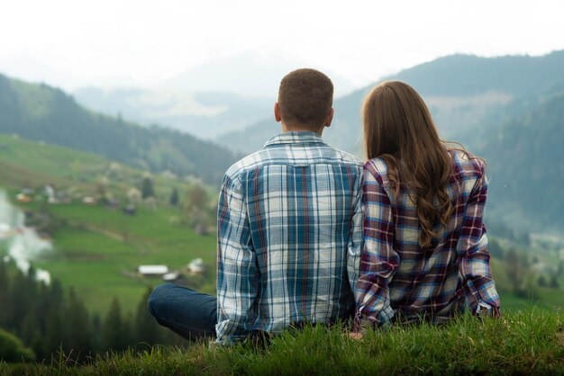 Couple of hikers relaxing sitting in Carpathian mountains enjoying landscape.  Summer vacation