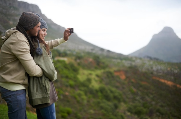 Couple hiking selfie and mountains for travel journey and adventure with photography and mock up space Happy people with love hug and profile picture for trekking in winter and nature tourism