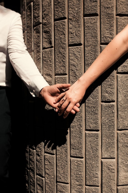 couple hold hands on a background of stone background wedding bride and groom wedding rings