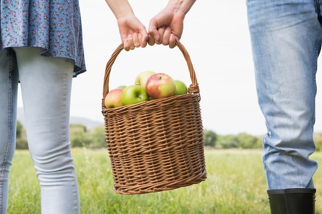 Couple holding basket full of apples 