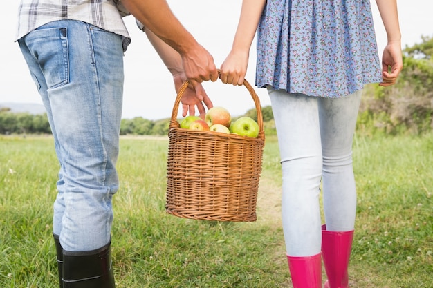 Couple holding basket full of apples 