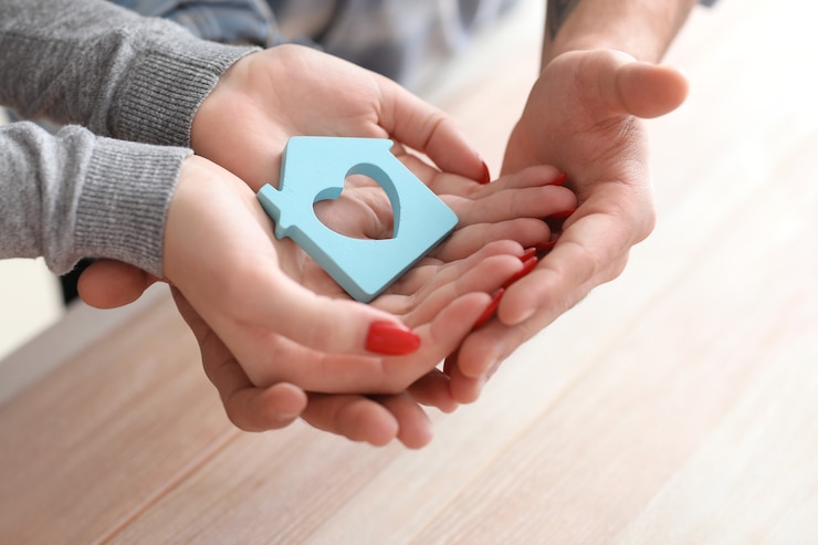 Photo couple holding figure of house. property insurance concept