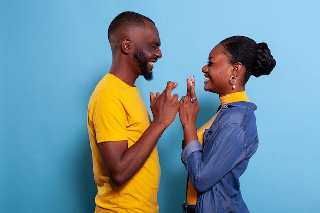 Couple holding fingers crossed to wish for good luck and fortune in front of camera. Positive girlfriend and boyfriend hoping for miracle, feeling excited about future. Superstitious lovers