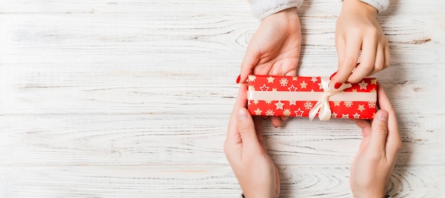 couple holding a gift box on wooden table. Flat lay