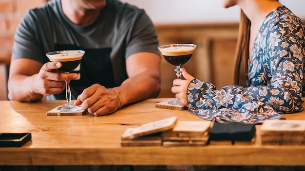 Photo couple holding glass with espresso martini cocktail, decorated with coffee bean. smooth image with shallow depth of field.