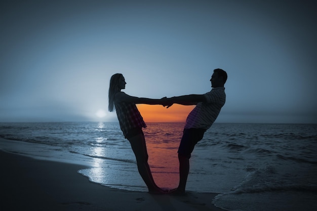 Couple holding hands on balcony against romantic couple at sunset