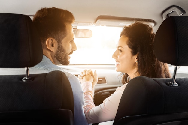 Couple holding hands in car sharing loving moment and looking at each other back view