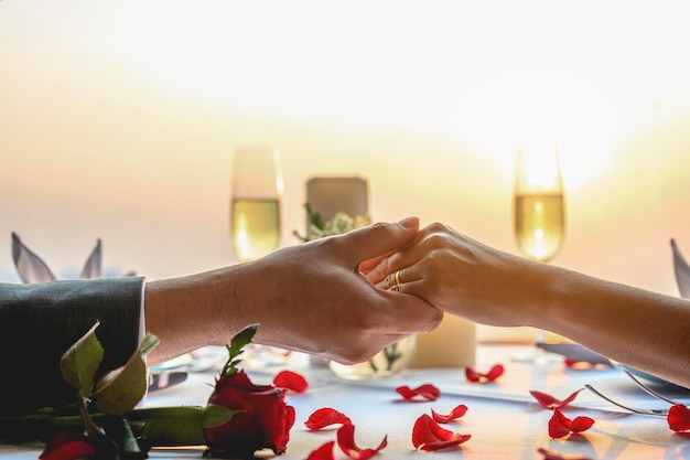 Coppia tenendosi per mano con una cena al ristorante in vista del tramonto. san valentino, coppia, luna di miele, cena, vino, concetto romantico.