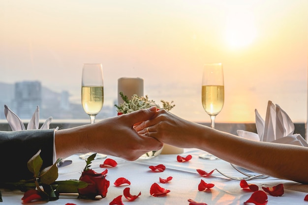 Couple holding hands having a dinner date at restaurant in sunset view. Valentine's, Couple, Honeymoon, Dinner, Wine, Romantic concept.